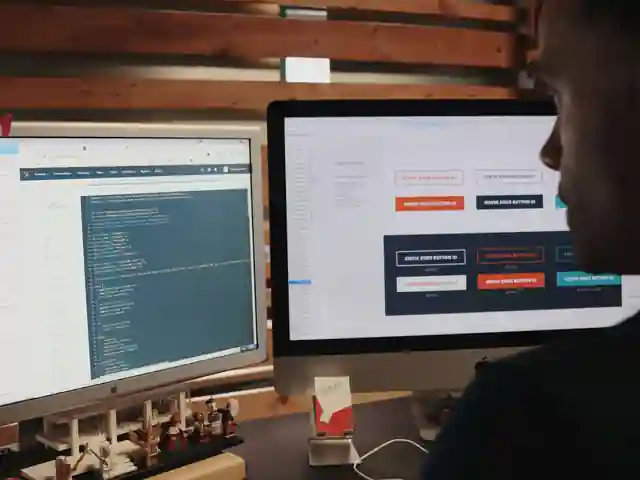 A web designer working across two screens at a studio desk